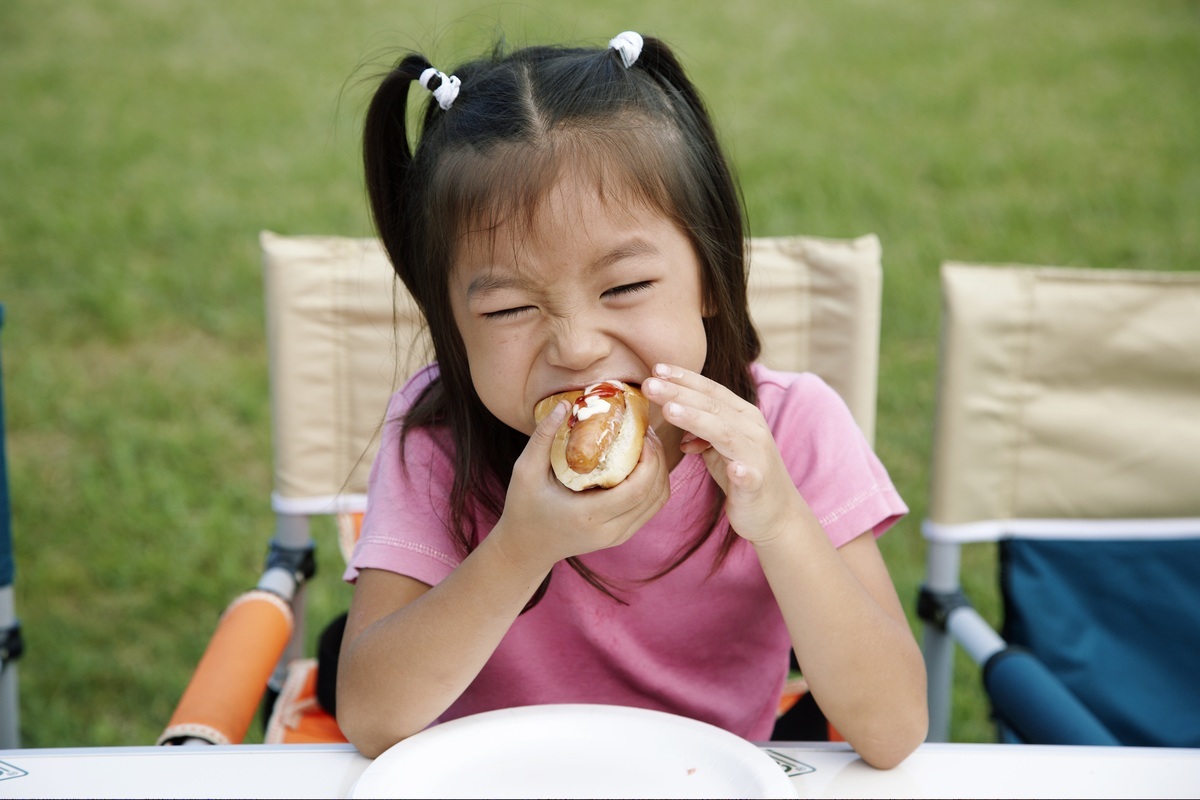 Criança comendo um hot-dog