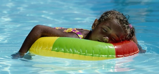 Criança dormindo na boia dentro da piscina - GettyImages