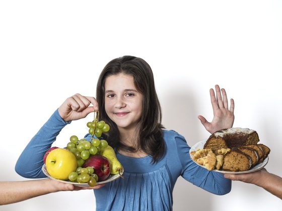 Criança recusando um bolo e pegando um cacho de uvas - foto: Circlephoto/ShutterStock.com Criança recusando um bolo e pegando um cacho de uvas - foto: Circlephoto/ShutterStock.com