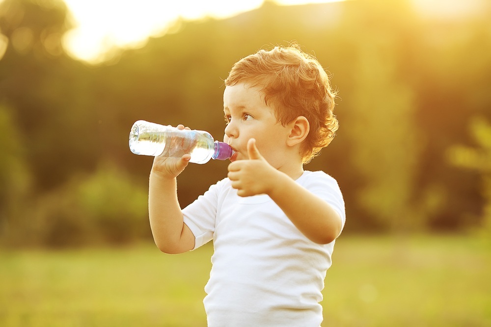 Criança bebendo água na garrafa e fazendo sinal de positivo - foto: Selins/ShutterStock.com Criança bebendo água na garrafa e fazendo sinal de positivo - foto: Selins/ShutterStock.com