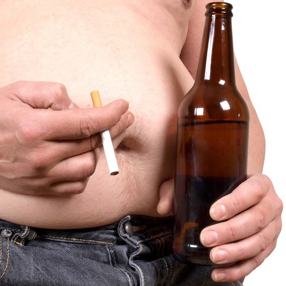 Homem obeso segurando cigarro e garrafa de cerveja - grynold / ShutterStock Homem obeso segurando cigarro e garrafa de cerveja - grynold / ShutterStock