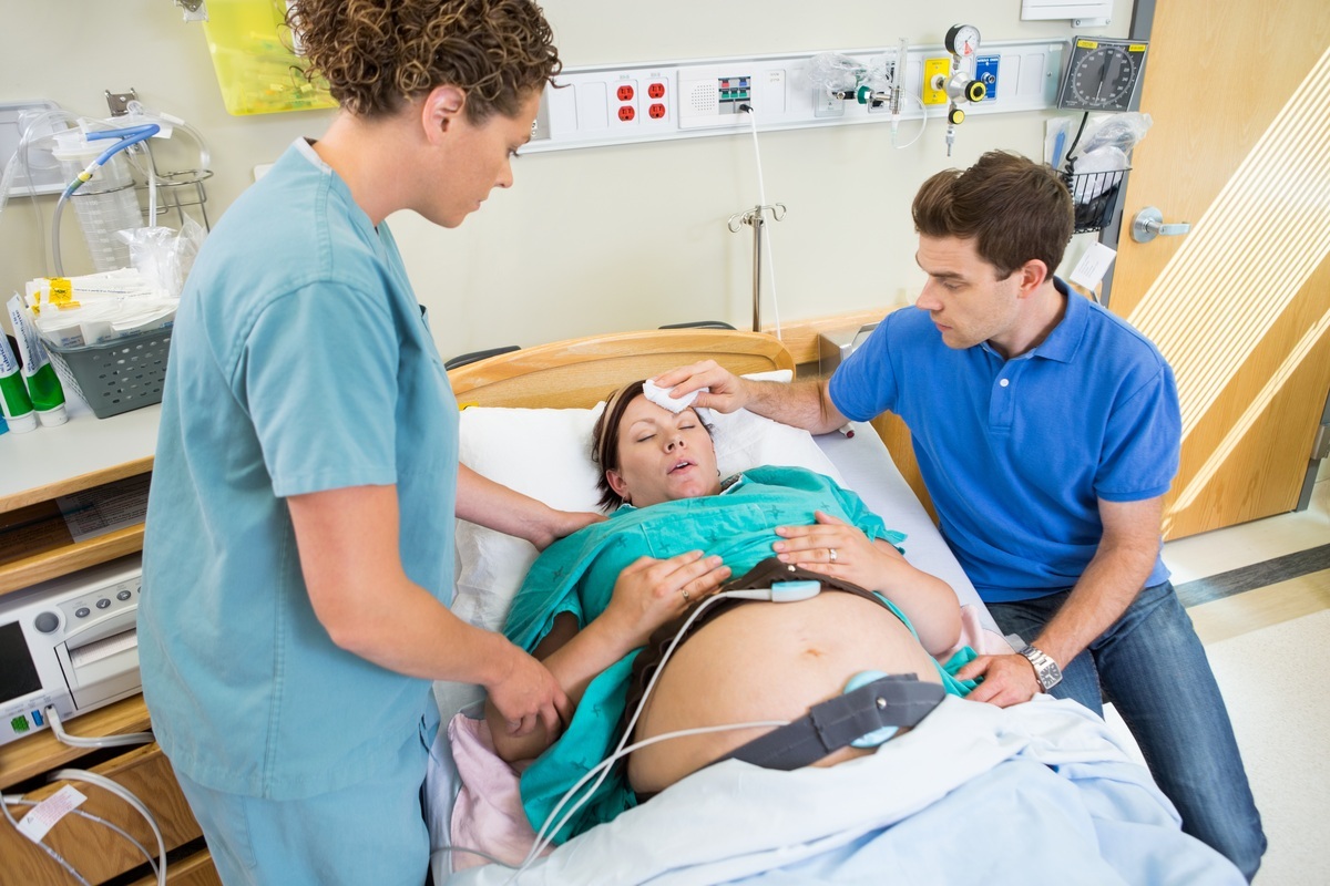 Mulher em trabalho de parto acompanhada de enfermeira e do marido - foto: Tyler Olson/ShutterStock.com