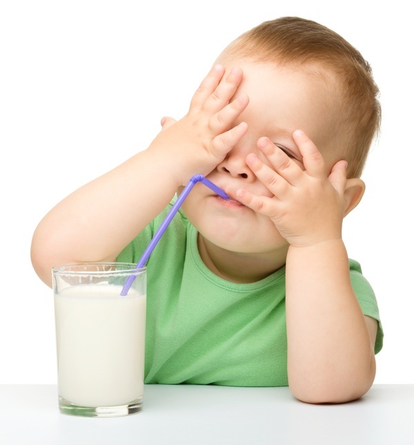 Bebê bebendo leite com canudinho e com as mãos tapando o rosto - foto: Serhiy Kobyakov/ShutterStock.com