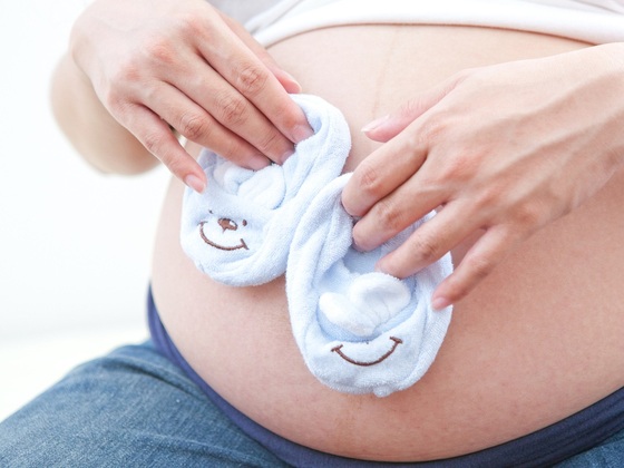Mulher grávida segurando sapatinhos - foto: Wong Mei Teng/ FeeImages.com