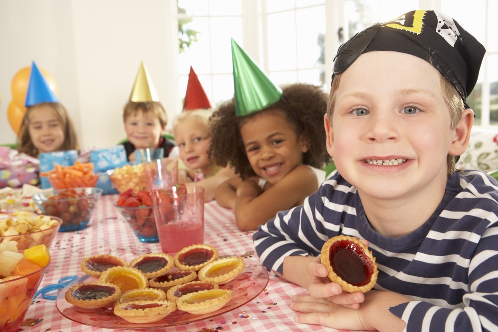 Festa de aniversário em casa com crianças sentadas à mesa - foto: Monkey Business Images/ShutterStock.com