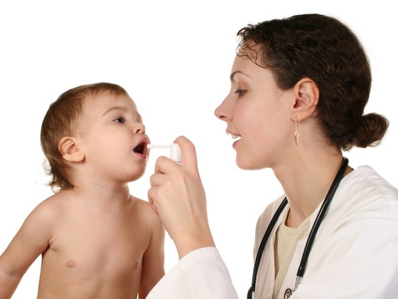 Médica borrifando remédio na boca da criança - Losevsky Photo and Video / ShutterStock