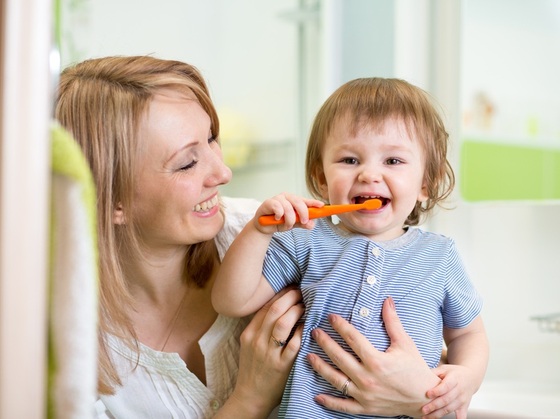 Mãe observando criança escovando os dentes