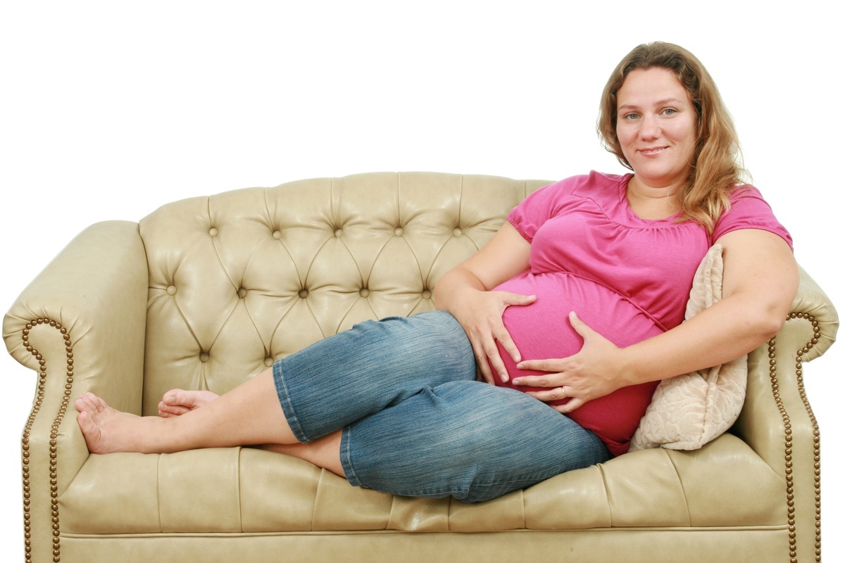 Mulher grávida sentada no sofá - foto: val lawless/ShutterStock.com