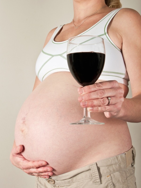 Mulher grávida segurando um copo de vinho - Foto: fasphotographic/ShutterStock.com