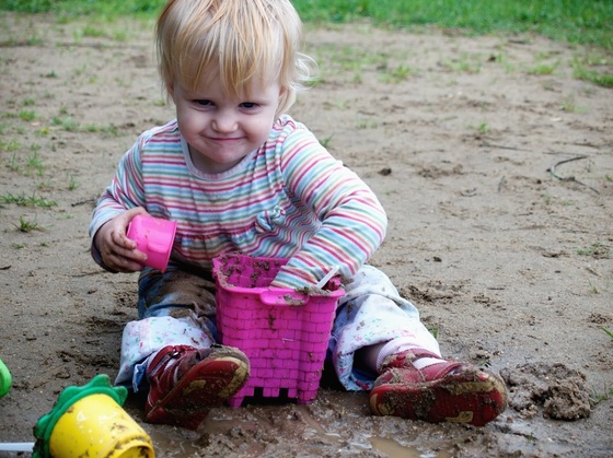 Bebê brincando no chão de areia encharcado - foto: liseykina/ShutterStock.com
