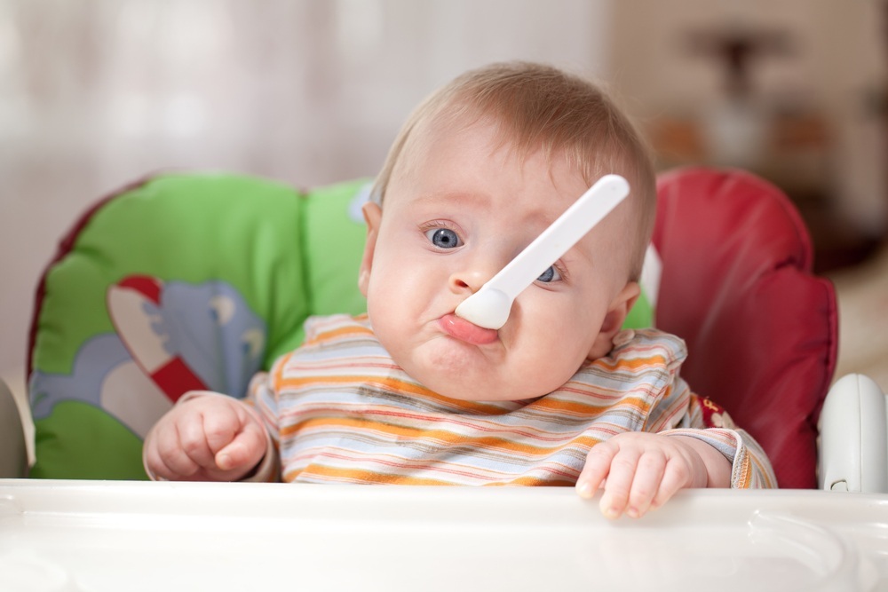 Bebê com colher na boca fazendo cara de triste - foto: gresei/ShutterStock.com Bebê com colher na boca fazendo cara de triste - foto: gresei/ShutterStock.com