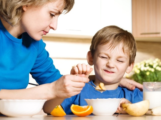 Mãe dando comida para seu filho que não está querendo comer - Larisa Lofitskaya / ShutterStock